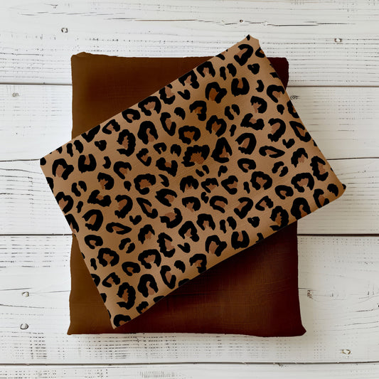 Gefalteter Stoff mit klassischem Leopard-Muster „Leo“ in Camel und Schwarz auf hellem Hintergrund – ideal für Mode und Accessoires.