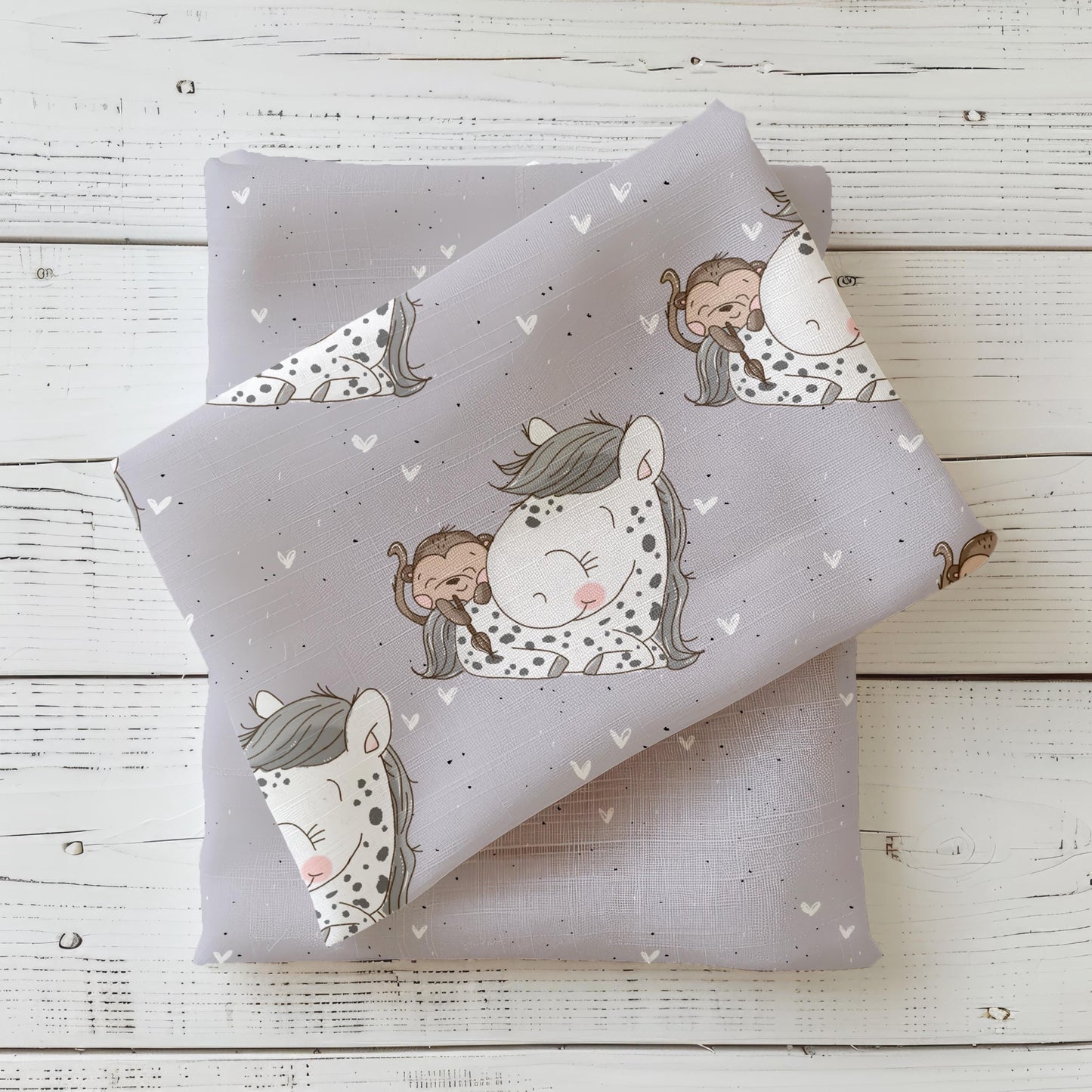 Gefalteter Kinderstoff Little Friends – Pony & Affe von Schnubbirella in Rosa-Grau auf einem unifarbenen Kombistoff, fotografiert als Stoff-Mockup auf weißem Holzhintergrund.