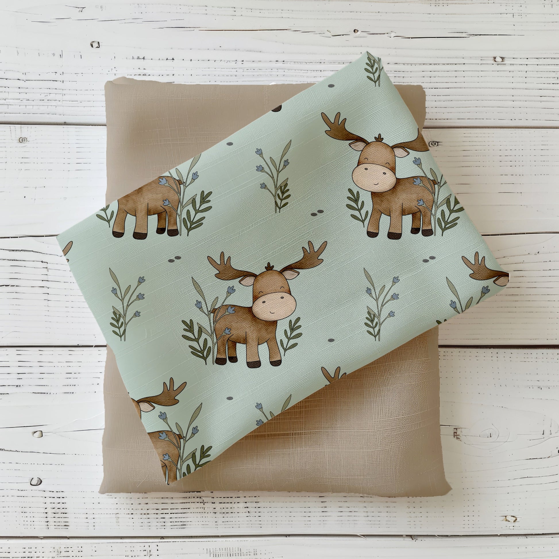 Mockup: Stoff „Lucas der Elch“ – braune Elch-Motive auf salbeigrünem, leicht gesprenkeltem Hintergrund mit Zweigen; Stoffkachel diagonal auf Uni in Taupe als Kombistoff.