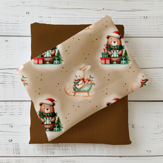 Weihnachtsstoff „Merry Christmas“ mit Bären, Hase im Schlitten und Geschenken auf beigem Hintergrund für festliche DIY-Projekte.