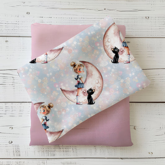 Kinderstoff mit einem Mädchen mit blonden Haaren im Dutt in einem weiß-blauen Kleid, hohen Socken und Turnschuhen mit einer schwarzen Katze daneben. Beide stehen vor einem Mond. Der Hintergrund ist in einem hellen Blau mit Glimmereffekt.