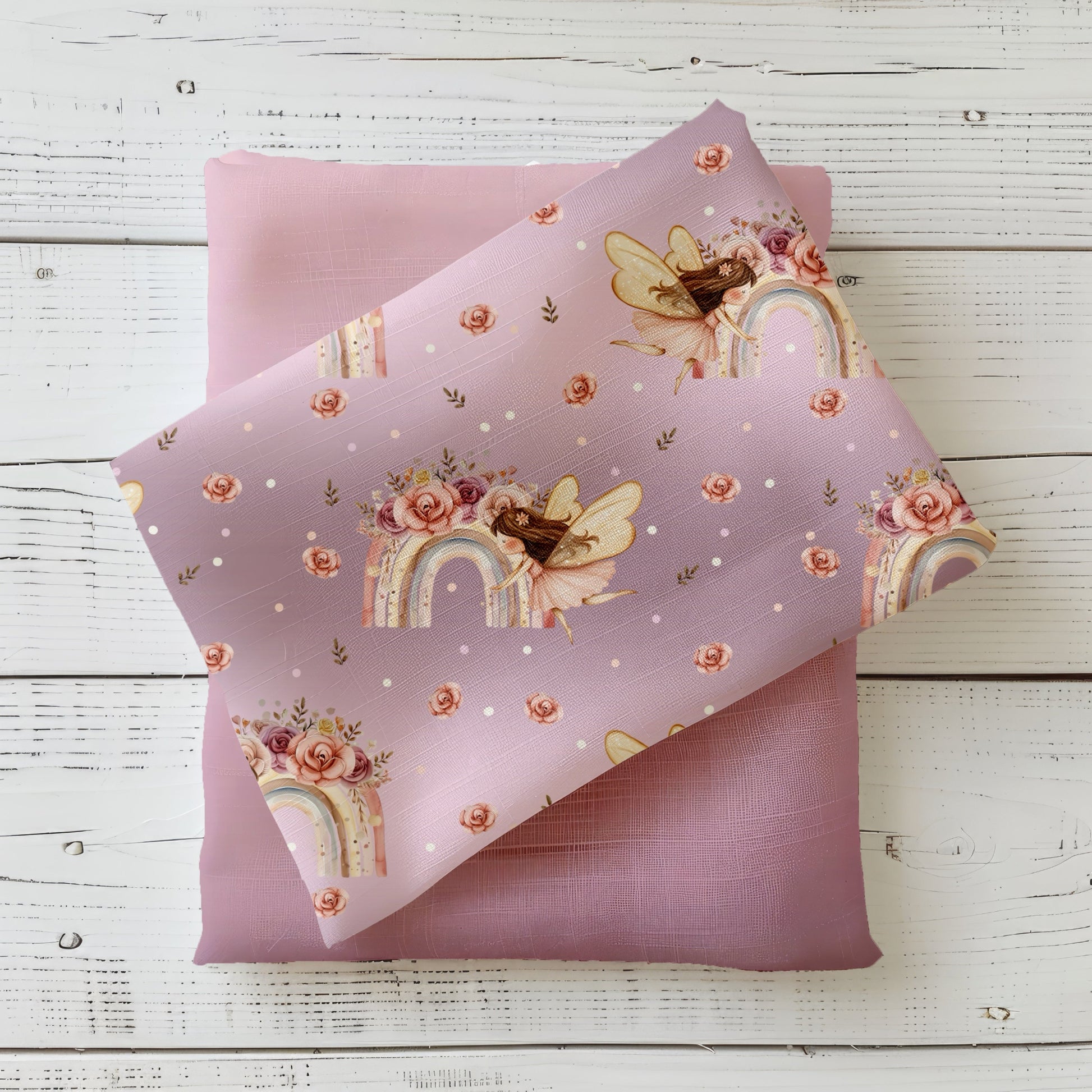 Regenbogenfee Kinderstoff dekorativ auf hellem Holzhintergrund drapiert – Mädchenstoff in Altrosa mit Fee und Blüten