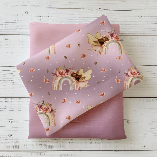 Regenbogenfee Kinderstoff dekorativ auf hellem Holzhintergrund drapiert – Mädchenstoff in Altrosa mit Fee und Blüten