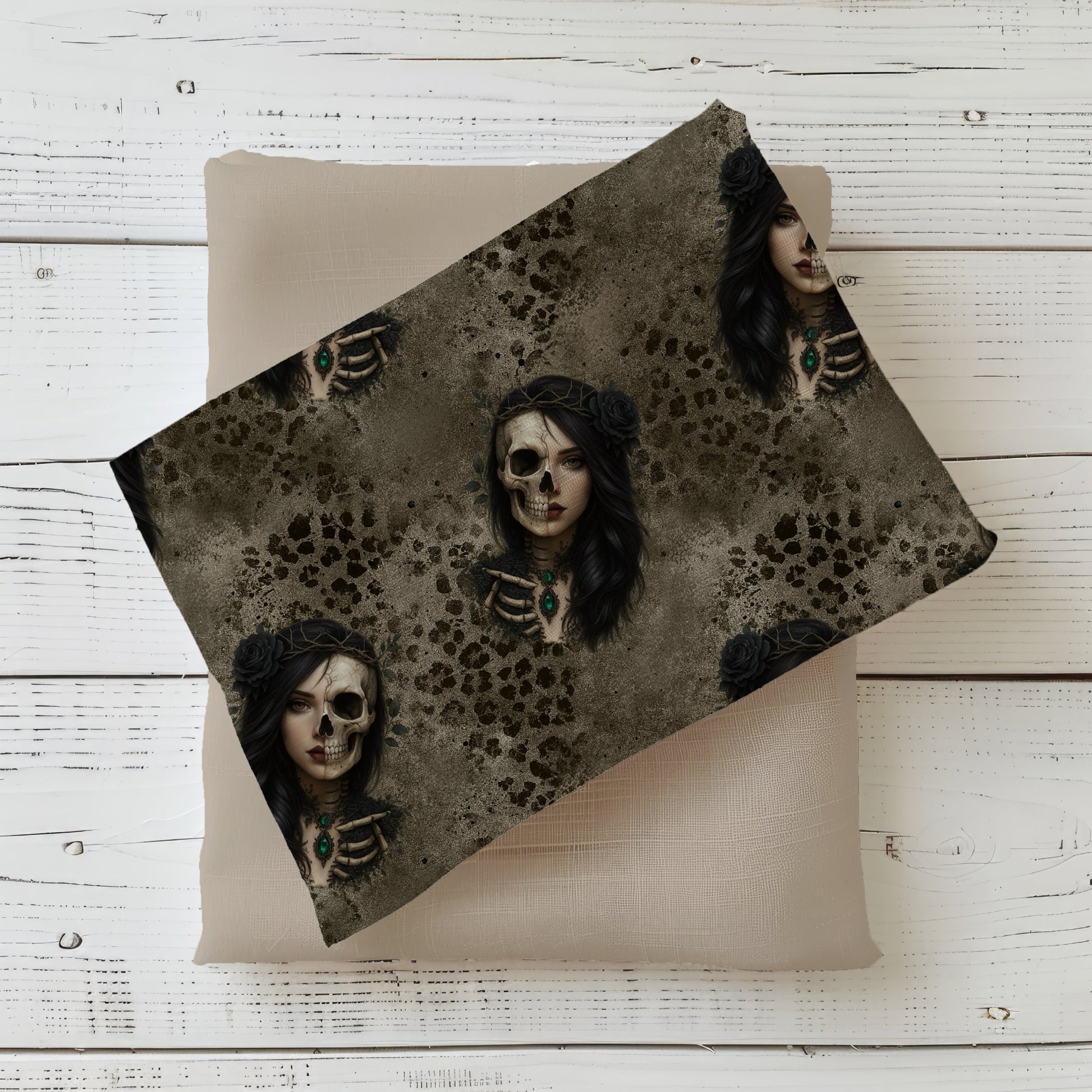Gefalteter Schattenprinzessin Stoff – mystisches Frauenmotiv mit halb Skelett, schwarzem Haar, smaragdgrünem Anhänger und dunklem Strukturhintergrund, drapiert auf taupefarbenem Kombistoff