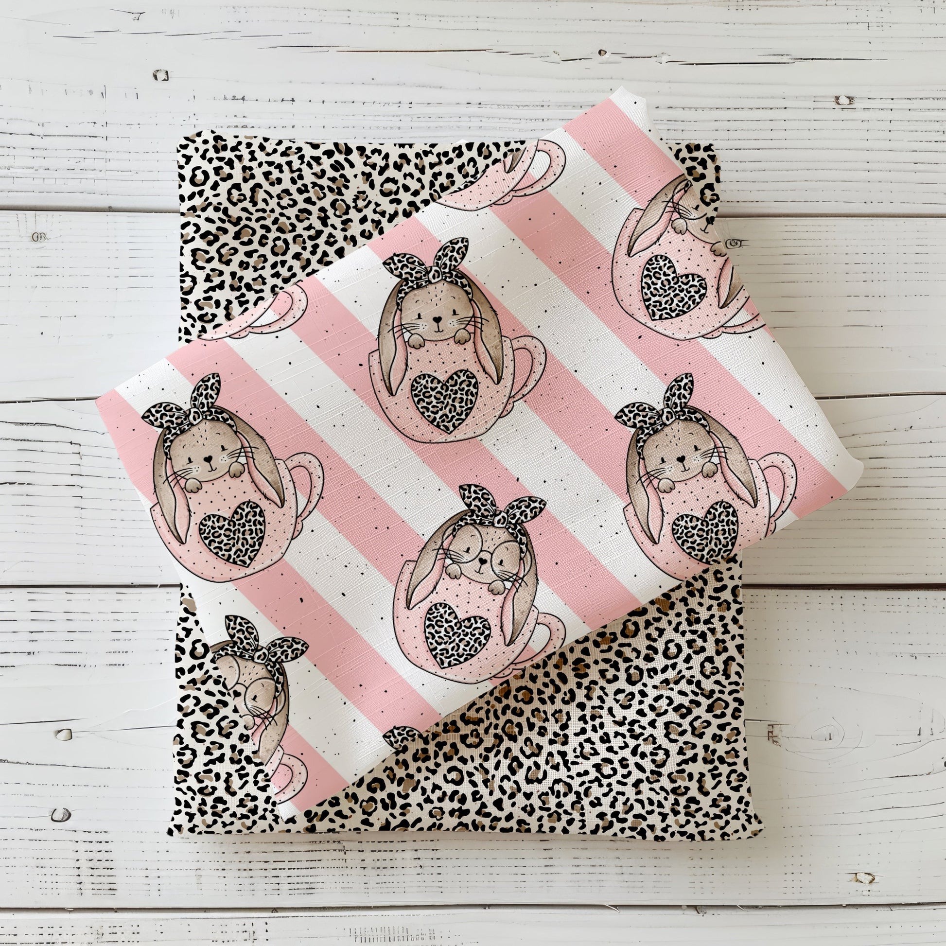 Gefaltetes Stoff-Mockup mit Design „Schlappohrlein“ – süße Häschen in Tassen mit Herzmotiv, Leo-Details und zarten Streifen in Rosé und Creme.