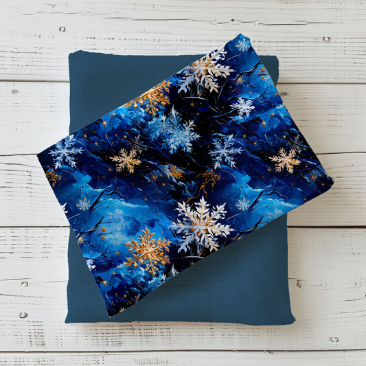 Edler Winterstoff „Schneeflocken“ mit weißen, blauen und goldenen Schneeflocken auf tiefblauem Hintergrund.