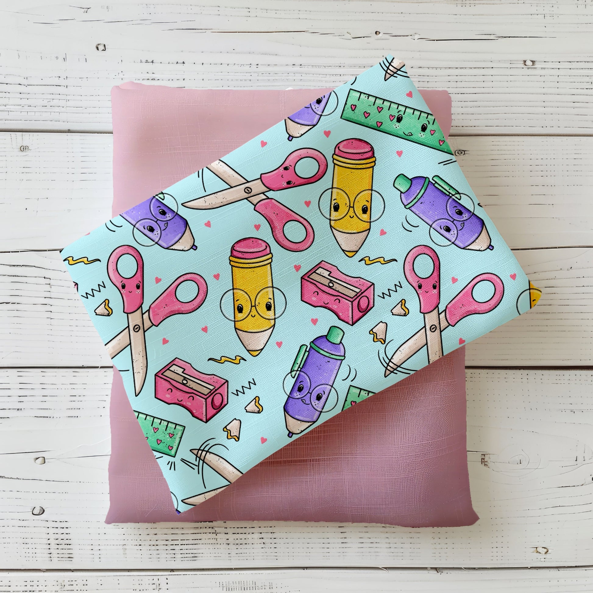 Bunter Stoff „Schreibzeug“ mit Scheren, Stiften, Linealen und Herzdetails, dekorativ auf einem Stoffstapel drapiert – verspieltes Katzengold-Design für kreative Nähprojekte.