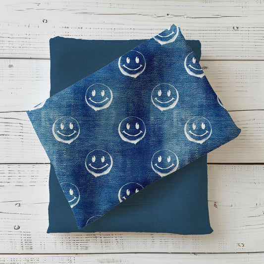 Gefalteter Stoff des Designs „Smiley – Denim blau“ mit durchgehendem Smiley-Muster.
