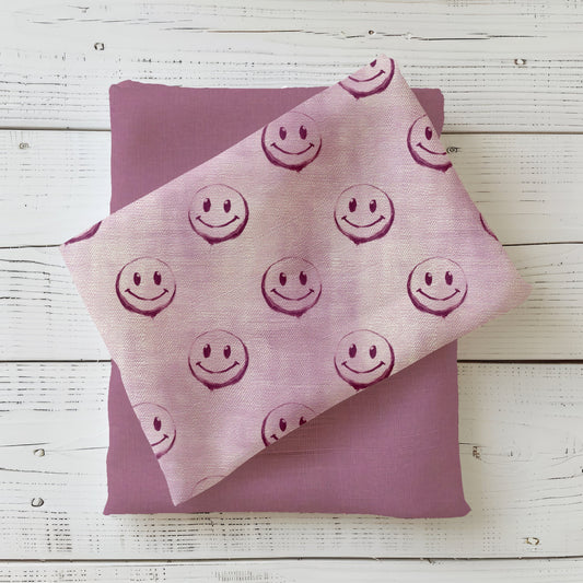 Gefalteter Stoff des Designs „Smiley – denim rosa“ mit durchgehendem Smiley-Muster.