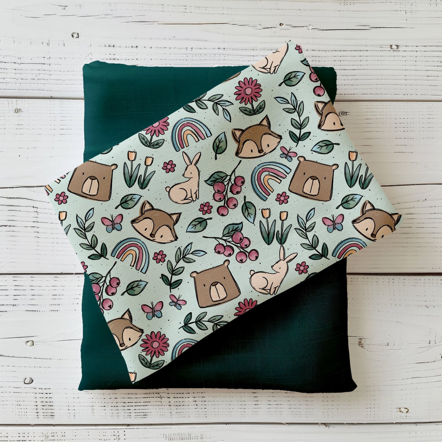 Frühlingsdesign Spring Parts mit Waldtieren, Blumen, Regenbögen und Beeren in sanften Farben, gefaltet präsentiert auf Holzuntergrund