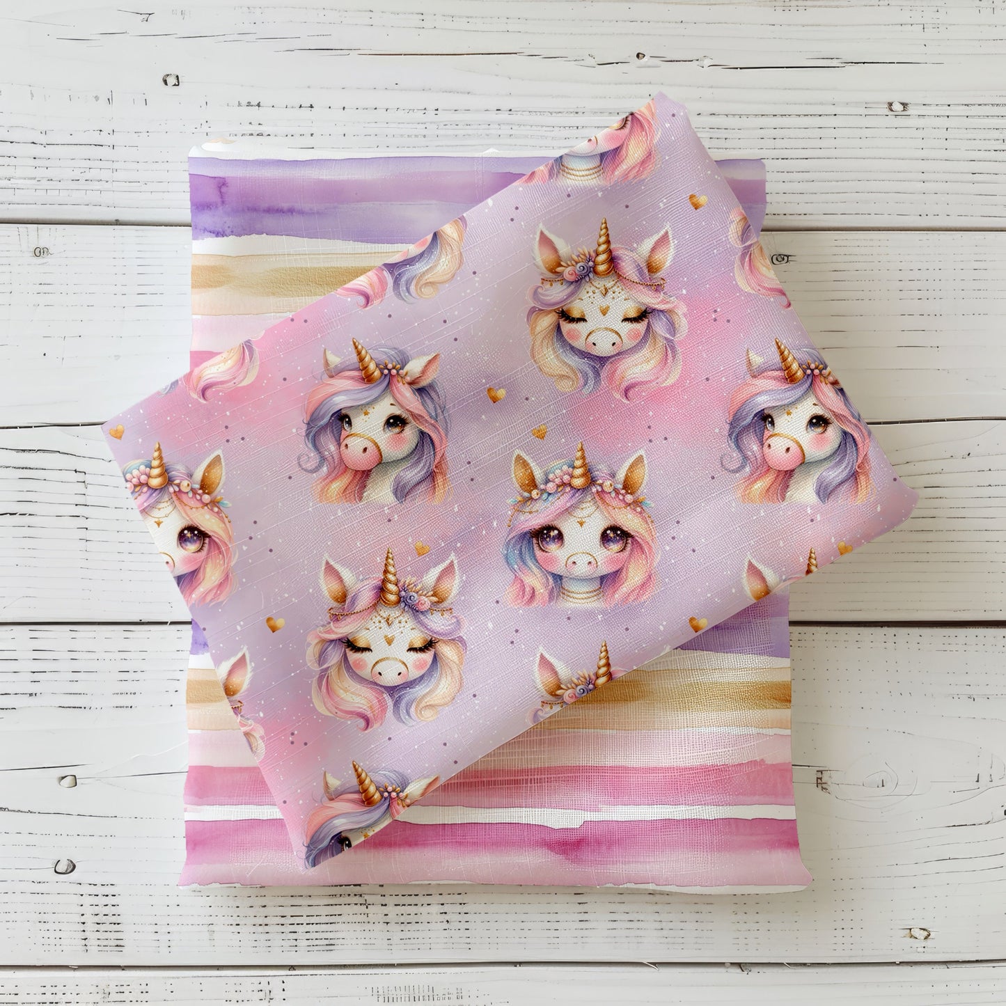 Unicorn Day Stoff dekorativ auf hellem Holzhintergrund drapiert – Einhorn Design in Rosa und Flieder mit Goldakzenten