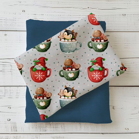 Winterstoff „Weihnachtstassen“ mit Pinguin, Lebkuchenmann und Weihnachtswichtel in bunten Tassen auf grauem Hintergrund.