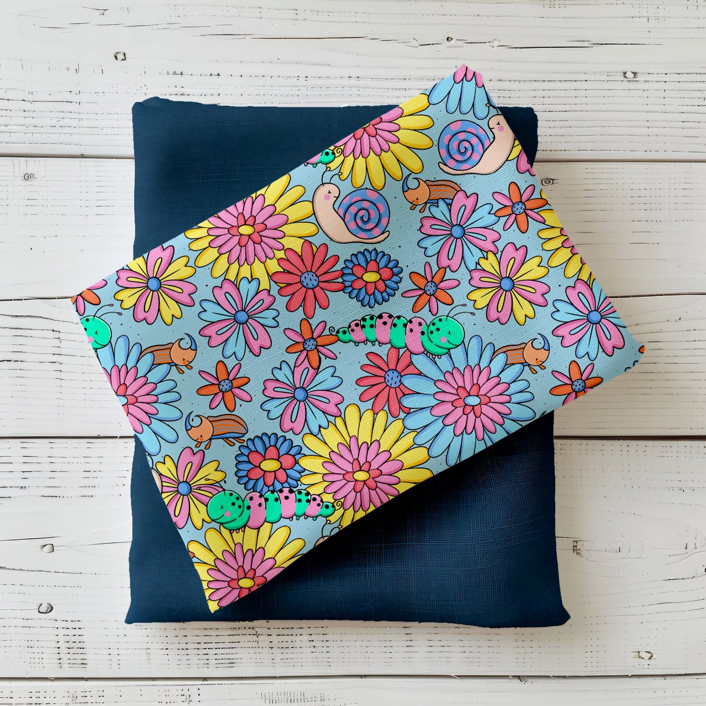 Wiesenkrabbler Kinderstoff mit bunten Blumen, Raupen und Schnecken von Katzengold-Designs auf blauem Hintergrund mit passendem Uni-Stoff.