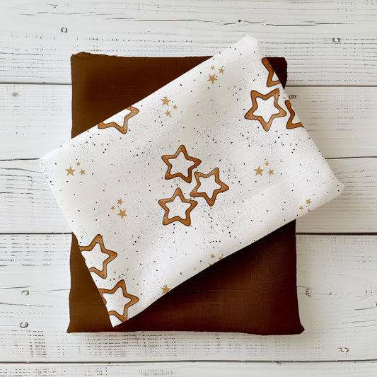 Design „Zimtsterne“ mit goldbraunen Sternplätzchen und kleinen goldenen Sternen auf hellem Hintergrund