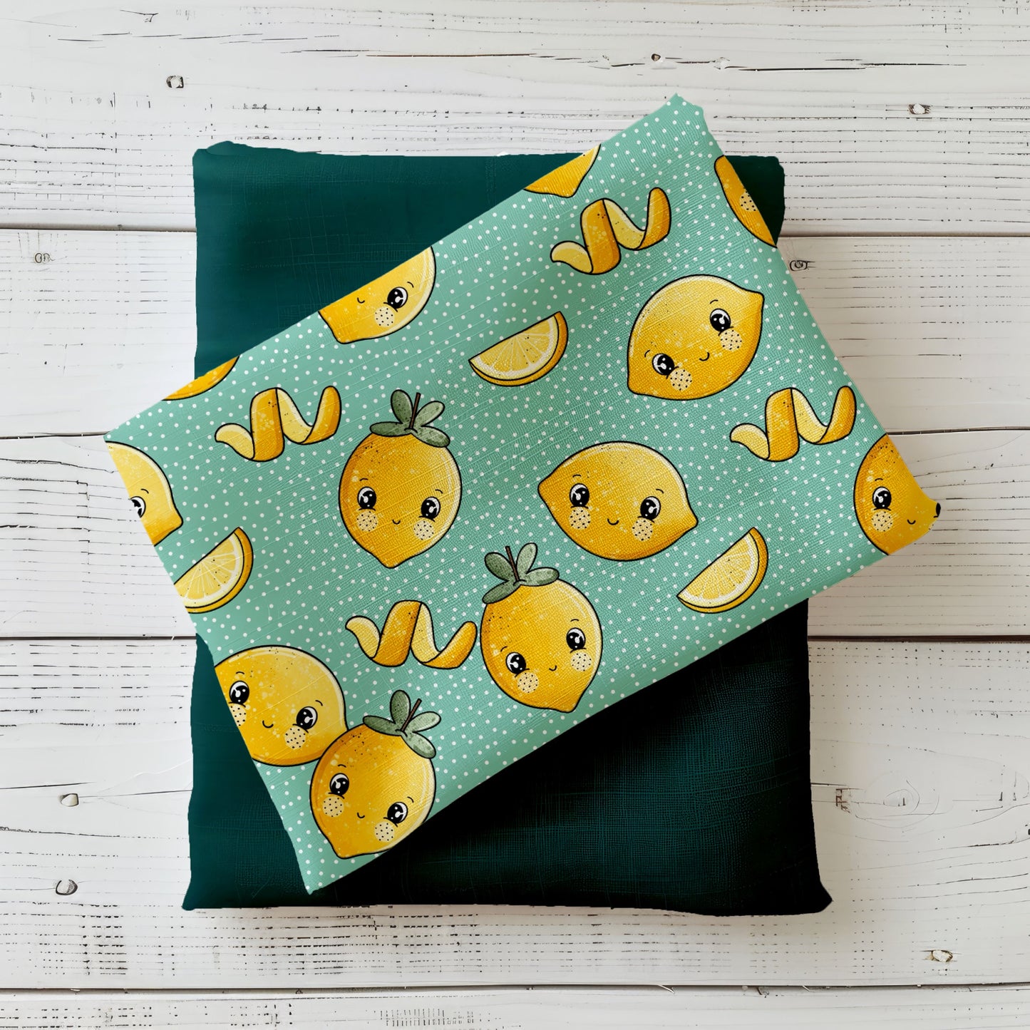 Zitönchen Mint Stoff – gelbe Zitronen mit Gesichtern auf mintfarbenem Hintergrund, drapiert auf dunkelgrünem Kombistoff