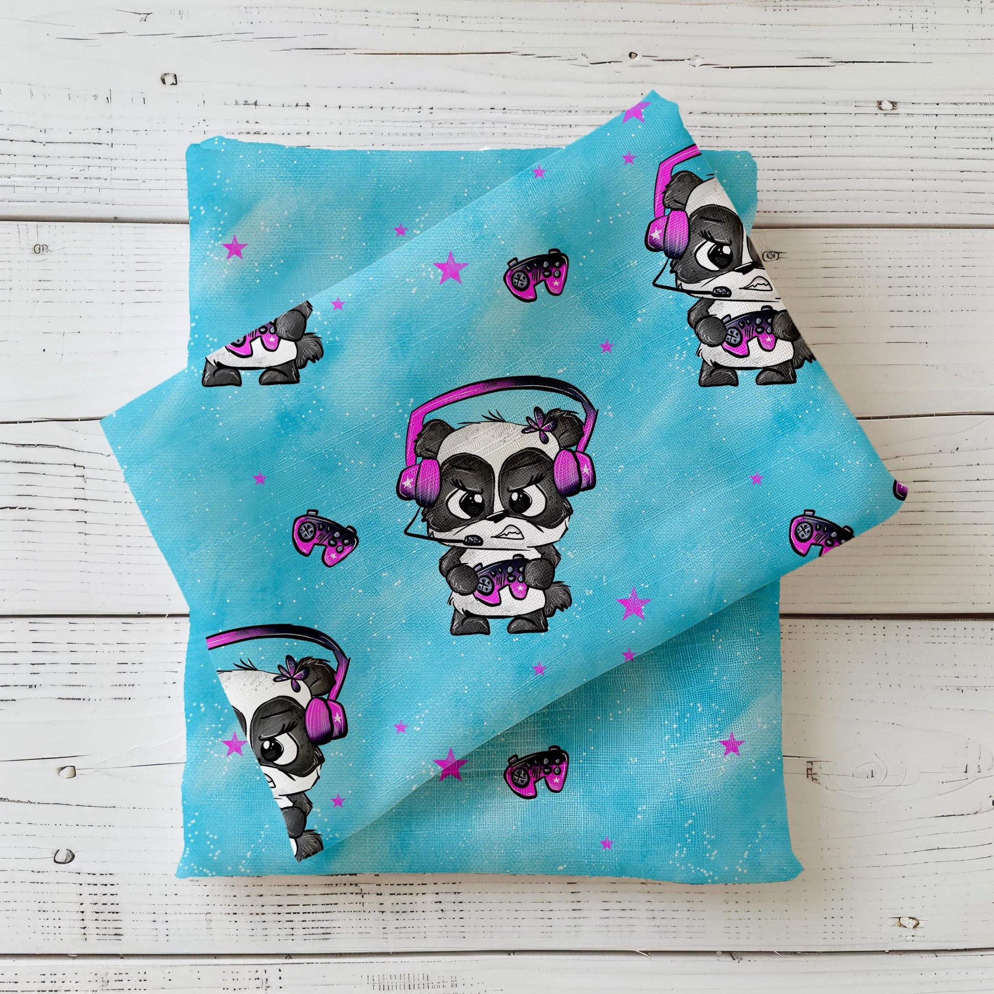 Mockup eines türkisfarbenen Kinderstoffs ‚Zockerpandi‘ von Schnubbirella, mit Gaming-Panda, Kopfhörern und Controller, drapiert auf dunklem Kombistoff.
