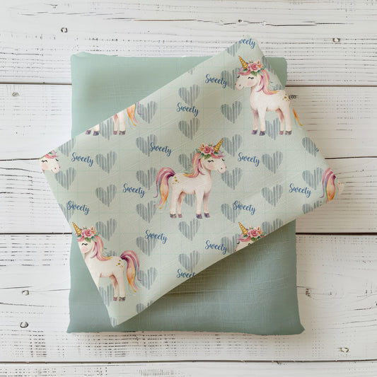 Mockup: Stoff „Zuckersüßes Einhorn“ – Einhörner mit Blumenkranz & Regenbogenmähne, Herzen im Karo und „Sweety“-Schrift auf mintfarbenem Hintergrund; Stoffkachel diagonal auf Uni in Salbei/Mint als Kombi.