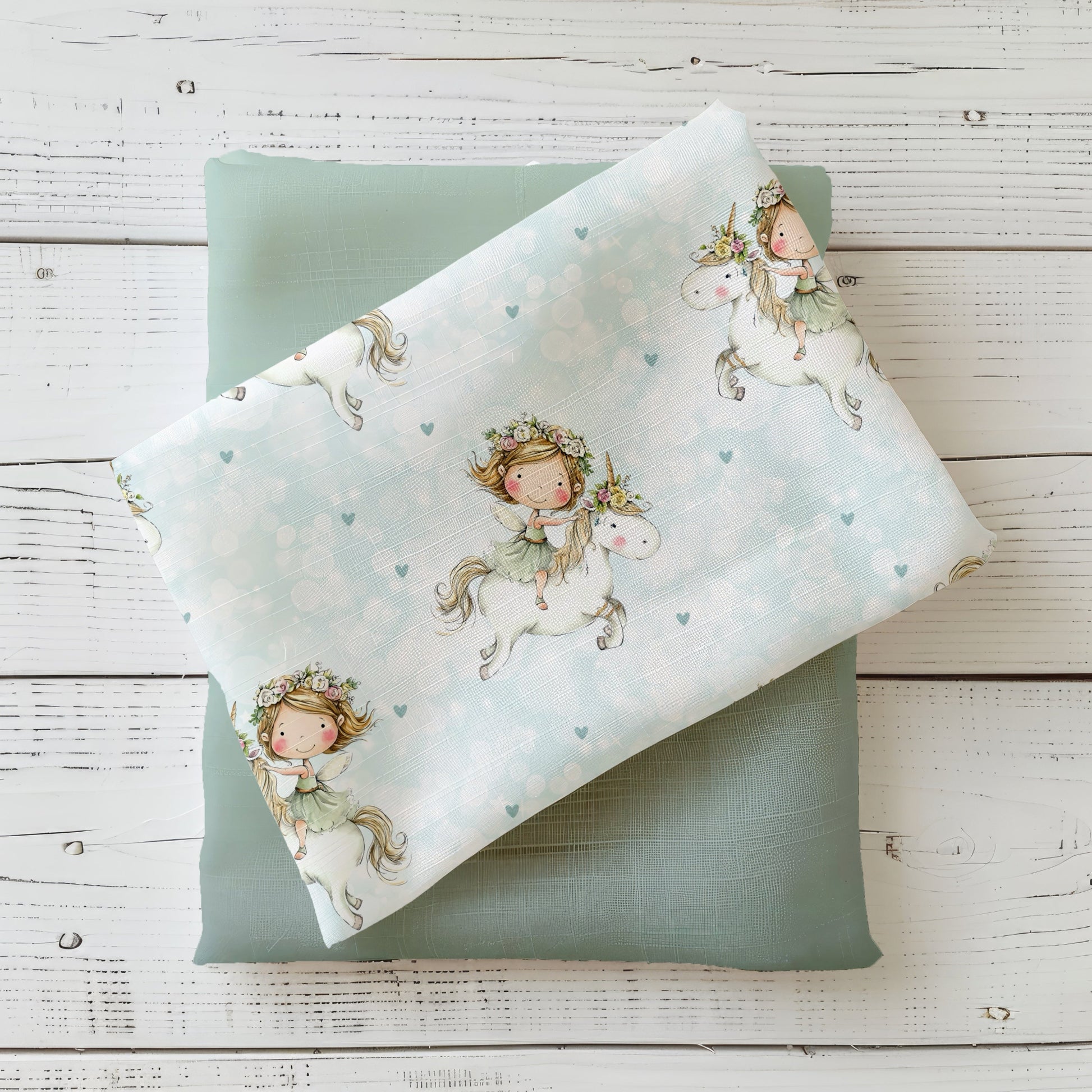 Flying Unicorn Kinderstoff dekorativ auf hellem Holzhintergrund drapiert – Einhorn Stoff in zarten Pastellfarben