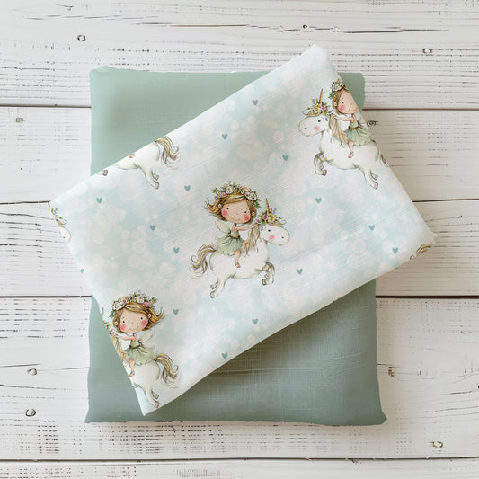 Flying Unicorn Kinderstoff dekorativ auf hellem Holzhintergrund drapiert – Einhorn Stoff in zarten Pastellfarben